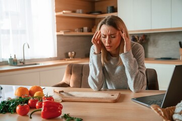 Tired, having headache. Beautiful young woman is on the kitchen