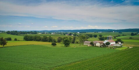 Fototapeta na wymiar Drone View of Amish Countryside With Barns and Silos, a Patch Work of Corps and Farmlands