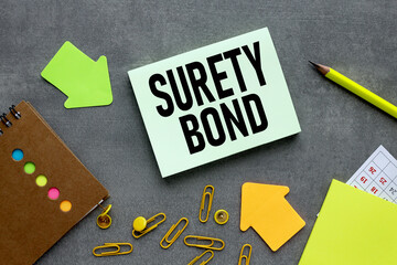 text on green sticker. on a gray background near bright stickers and paper clips SURETY BOND....