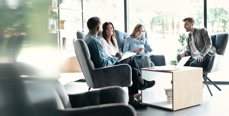 Interested happy colleagues sitting on chairs, listening to boss team leader, explaining working issues at meeting