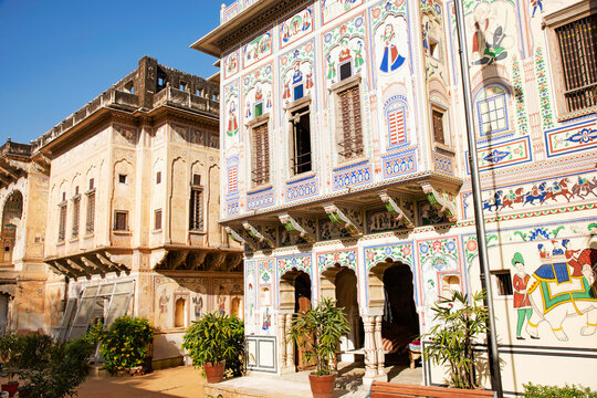 Colorful paintings and wooden windows on the outer wall of Seth Harmukhrai Sanehiram Chokhani Double Haveli, located in Mandawa, Shekhawati,  Rajasthan, India