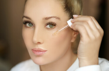 woman applying serum, lotion to her face