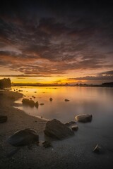 Unique rock formations on sandy Tanjung Layar Beach under dark cloudy sunset sky background