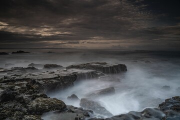 Breathtaking view of Karang Bokor Sawarna in Indonesia under dark cloudy sunset sky, long exposure