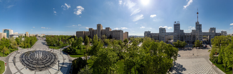 Fototapeta na wymiar Aerial panorama on Derzhprom and main Karazin National University buildings on Freedom Square with circle fountain, spring greenery and blue sky in Kharkiv, Ukraine