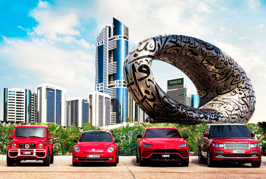 Dubai, United Arab Emirates – February 13, 2021: Fascinating cityscape with expensive luxury red cars in the parking  against the Museum of the Future with Arabic poetry and Dubai towers.
