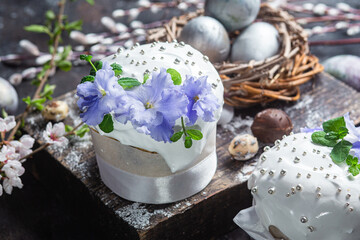 Fototapeta na wymiar Easter cake with meringue and violets on a dark background