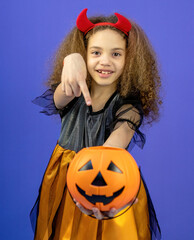 A beautiful and cute girl in a dress on a colorful purple background shows emotions, the concept of the Halloween holiday.