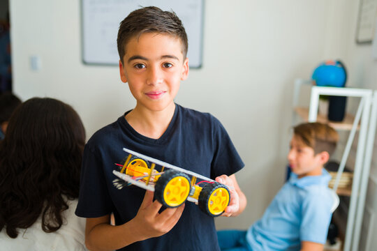 Smart teen student holding a robot prototype in school