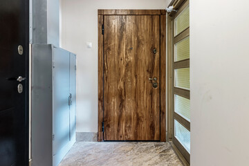 Entrance wooden door of natural color, in a multi-storey building. Entrance to the apartment