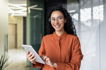 Portrait of successful hispanic woman inside office at workplace, businesswoman smiling and looking...
