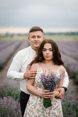 Couple standing and enjoys floral glade, summer nature. Loving couple holding bouquet of lavender flowers at sunset. Family hugging in purple lavender field. France, Provence. Honeymoon trip. Closeup.