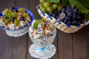 Creamy Grape salad. Homemade grape salad made with green and dark grapes, сream сheese, sour cream and chopped nuts served in a glass bowl with basket of fresh grapes on the background. Horizontal.