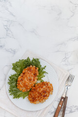 Pozharsky cutlets and lettuce leaf in a white plate on a marble background. Selective focus, top view, place for text - 593938486