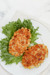 Pozharsky cutlets and lettuce leaf in a white plate on a marble background. Selective focus, top view - 593938498