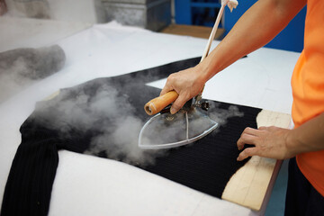 Workers in a garment factory are using an iron to iron clothes, production line