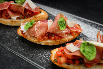 Savory Bruschetta with Salmon, Ham and Parmesan Cheese on Dark Background
