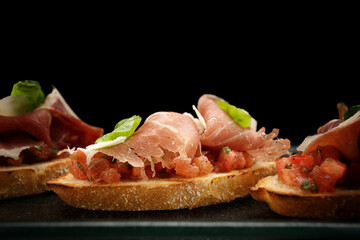 Savory Bruschetta with Salmon, Ham and Parmesan Cheese on Dark Background