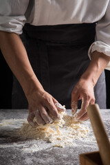 Obraz na płótnie Canvas A chef is kneading dough using eggs, kitchen dark background, professional photography light