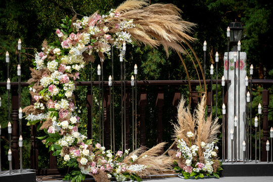 Beautiful round wedding arch decorated with flowers and greenery outdoors, copy space. Decorations for wedding ceremony in open air. Wedding round arch in rustic style decorated 
