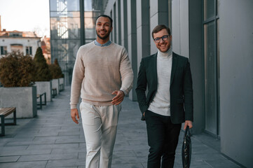 Walking together. Businessman in formal clothes is with black man outdoors in the city