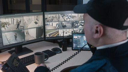 Security officer controls CCTV cameras with facial recognition in office, uses digital tablet and computers. High tech software with surveillance cameras playback on screens. Concept of social safety.
