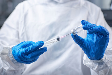 Doctor filling syringe with medication, Under syringes and bottles with injection solutions. The doctor injected the vaccine with a syringe.