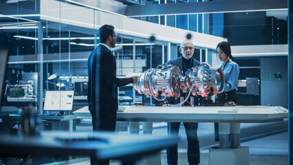 Software Developer, Project Manager and Machinery Operators Collaborate on a Prototype Turbine Engine, Standing with Laptop Computer in Scientific Technology Lab. Team Developing a New Electric Motor.