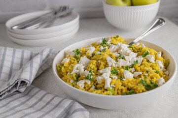 Curry rice with broccoli and feta cheese on a plate. Cooked with brown rice