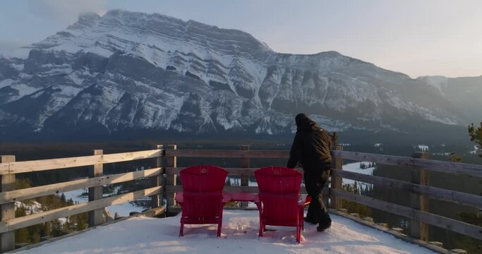 man sits on a red chair on Mount Rundle view point