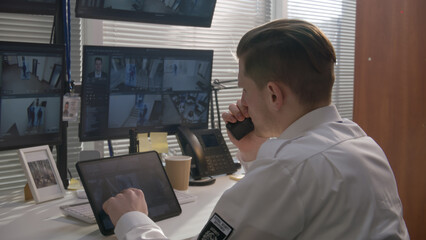 Security officer monitors CCTV cameras on computers and digital tablet, uses walkie talkie. Software showing footage of surveillance cameras on screens. High tech security. Concept of social safety.