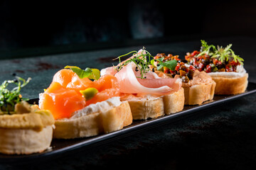bruschetta set, various bruschettas with toppings on black plate