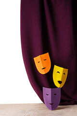 three theatrical masks made of colored paper against the background of a velvet curtain, copy...