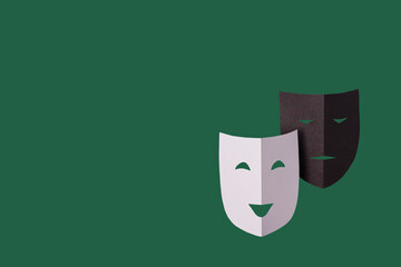 white and black theatrical masks on a green background, copy space, photo