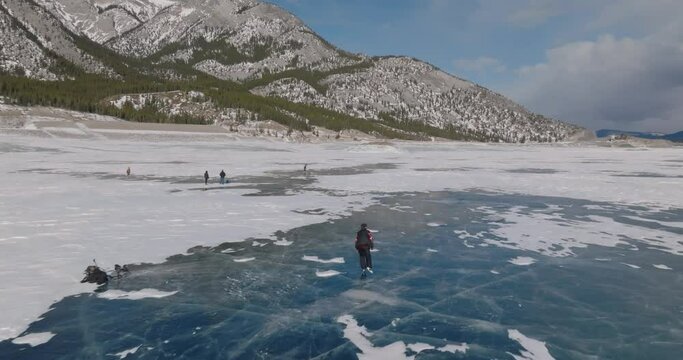 aerial view of man ice skating on frozen abraham lake in laberta, canada