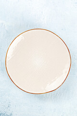 An empty white plate with a gold rim, top shot on a slate background, a modern ceramic dish