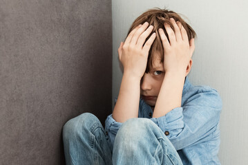 Scared little boy sitting at corner of room feeling sad and lonely. Child loneliness, Autism...