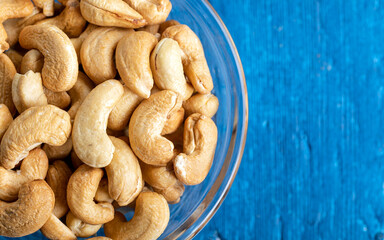 Tasty cashew nuts in a bowl on wooden table, top view.Bowl with cashew nuts on a wooden table, flat lay. 
