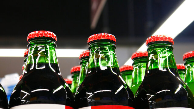 Close-up of many green glass bottles of juice or another beverage with red caps in a store