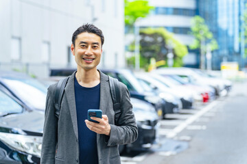 スマホを持って駐車場に立つ男性