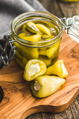 Peppers stuffed with cream cheese on cutting board.