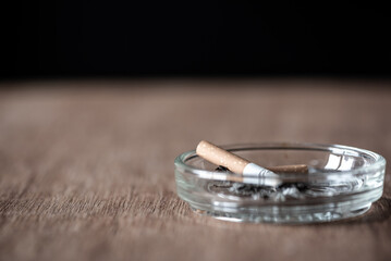 burning cigarette stick in ashtray on wood table