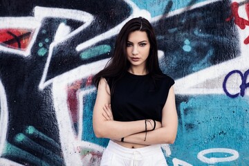 Confident pretty female standing in front of the graffiti wall