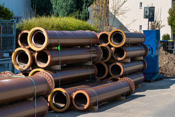 Brown ceramic pipes for laying water pipes are stacked on a construction site.
