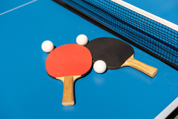 Table tennis rackets and a white plastic ball on a blue background.