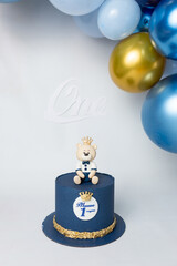A blue cake with a teddy bear on top with a crown on it. Cyrillic inscription 