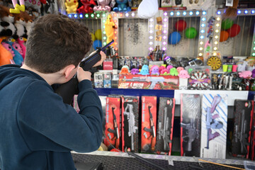 teenager with a rifle in a funfair