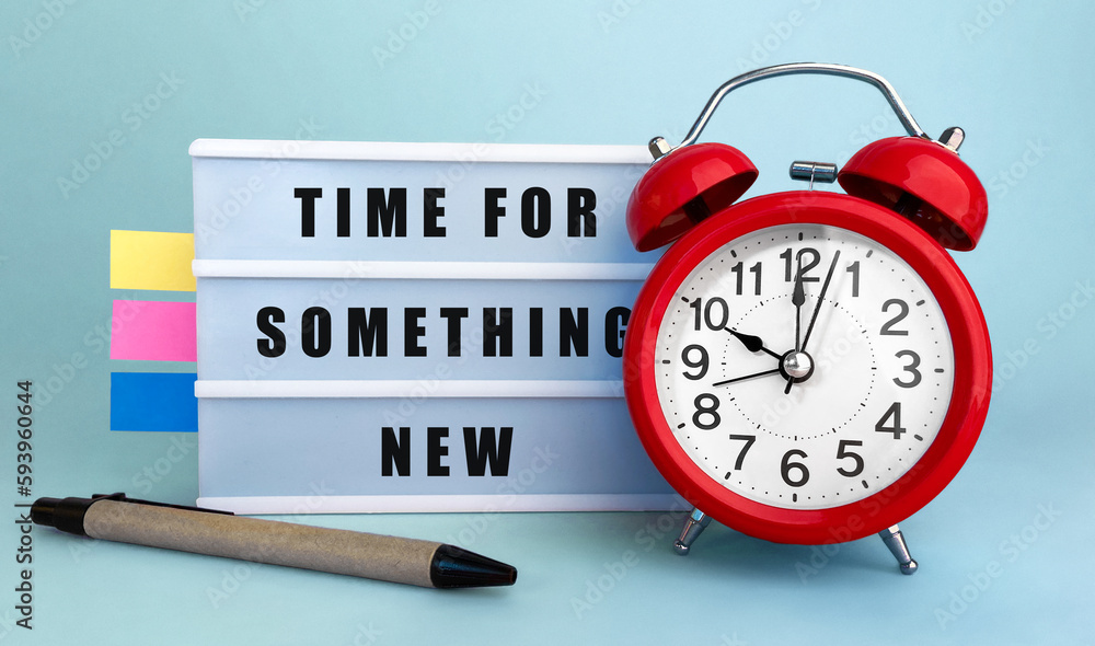 Poster text time for something new written on the lightbox with alarm clock and colorfull stickers on blue 