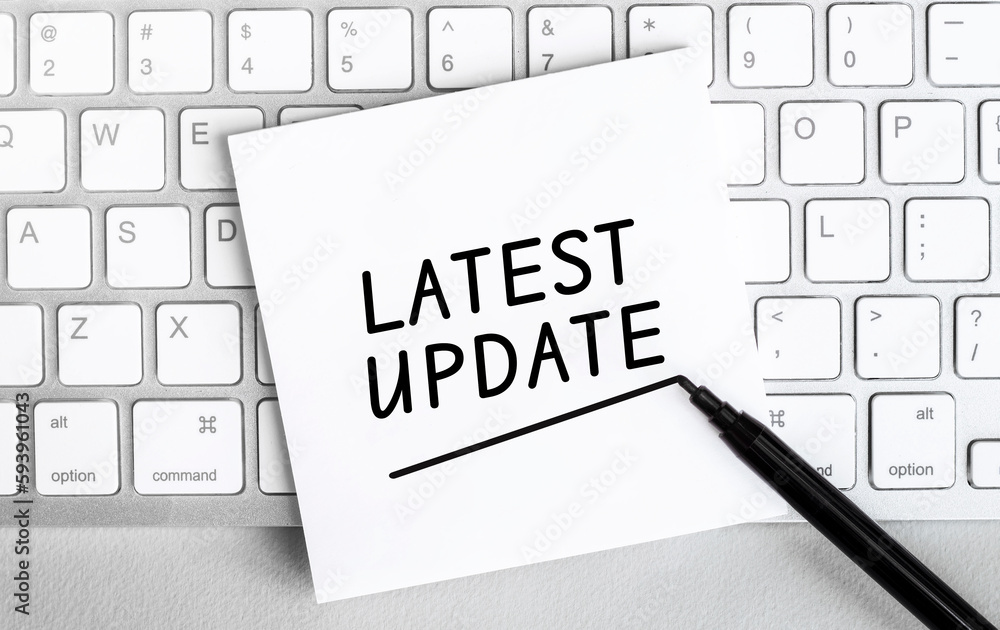 Poster white paper with text latest update lying on the keyboard