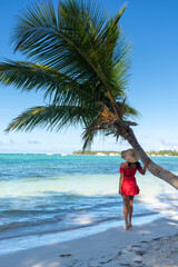 Dominican Republic of Punta Cana, a girl in a hat on the ocean with turquoise water and palm trees.